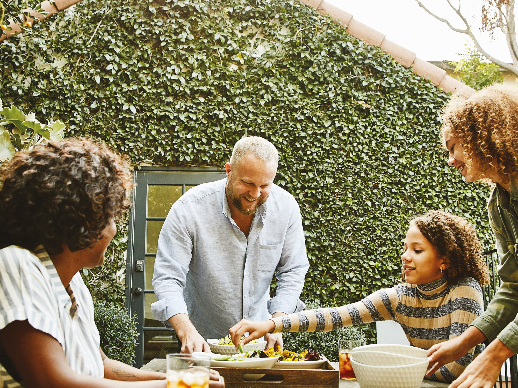 Family in backyard at picnic table eating hors d'oeuvres and drinking iced tea